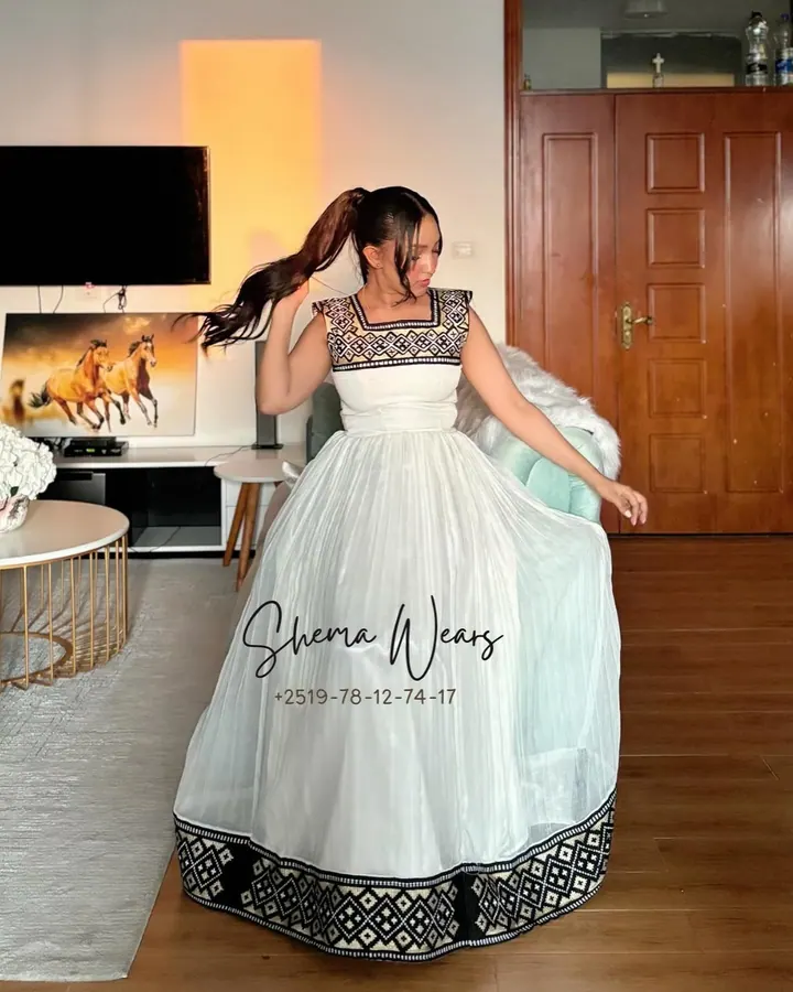 Model in a sleeveless white habesha kemis with a black and white geometric tibeb bodice and a black tibeb hem