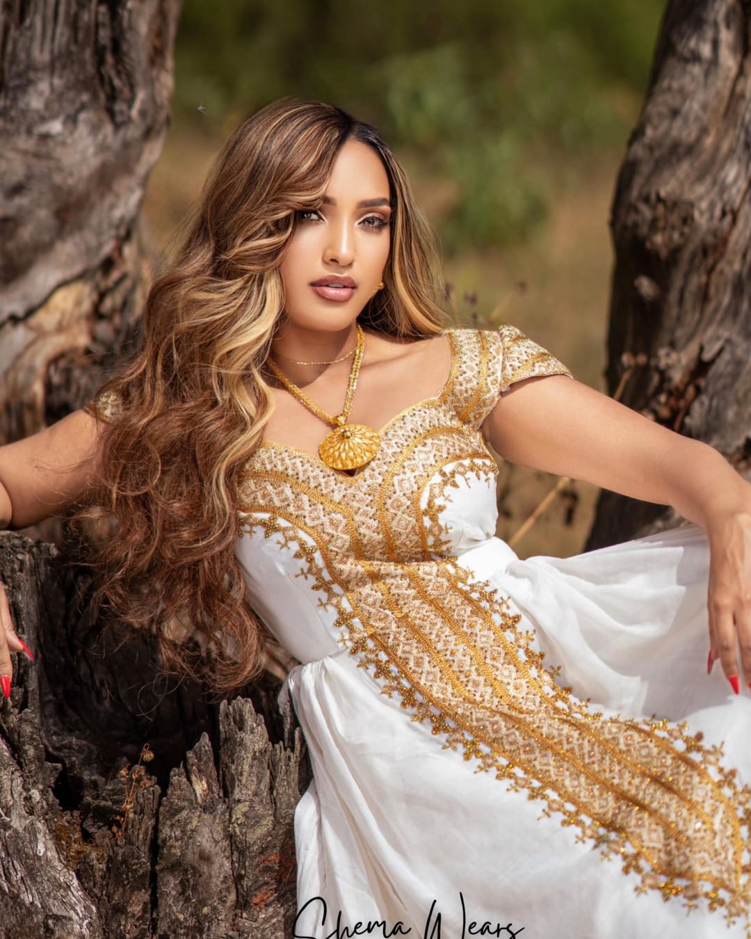 Model in a white habesha kemis with a gold tibeb bodice and a gold panel cascading down the skirt