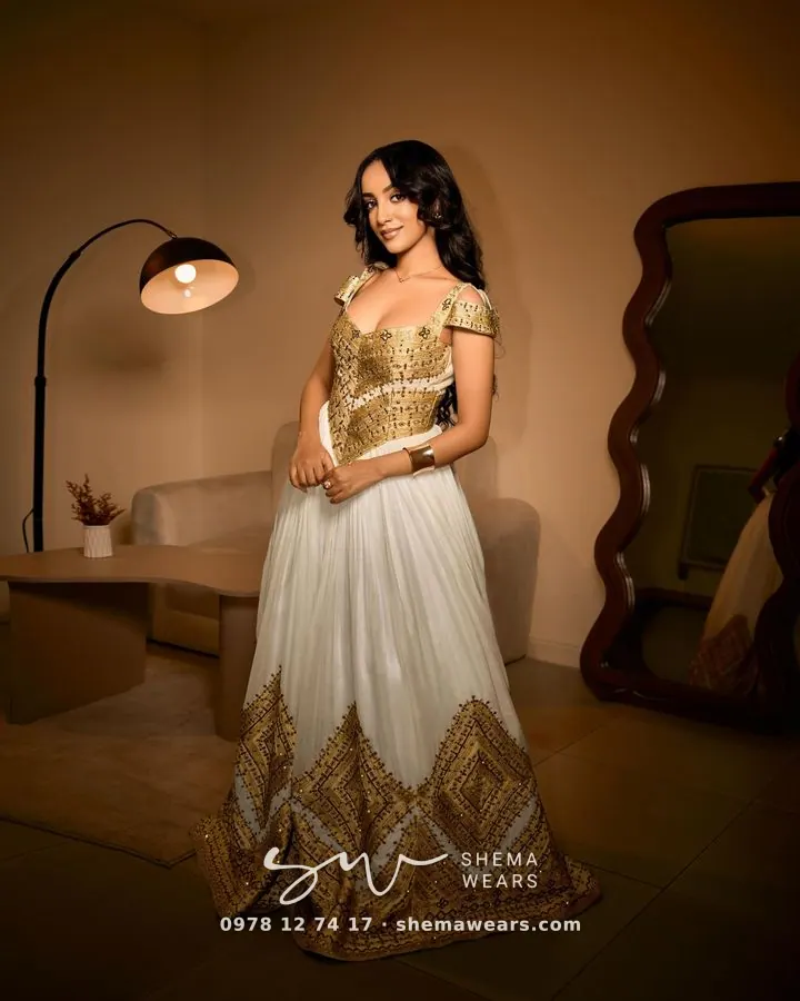 Model in a white ballgown habesha kemis with a gold tibeb bodice and a deep gold tibeb hem