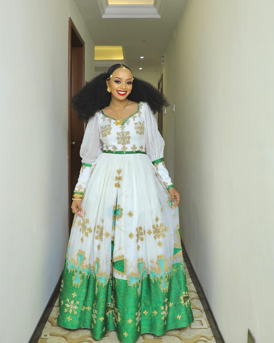 Bride in a white long-sleeve dress with green and gold embroidery and a green hem, for the melse