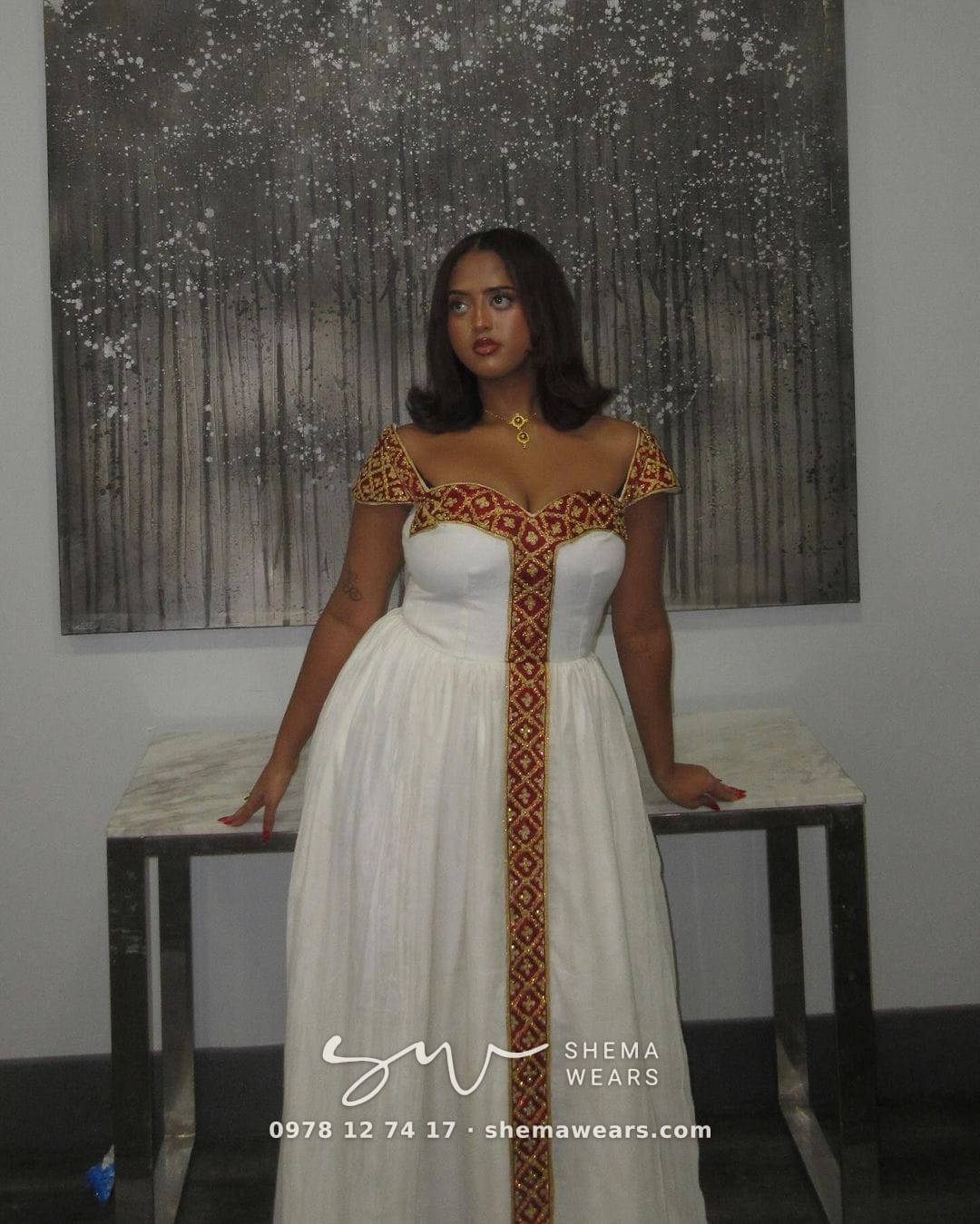 Model in a white habesha kemis with maroon and gold tibeb at the sweetheart neckline, cap sleeves and centre panel