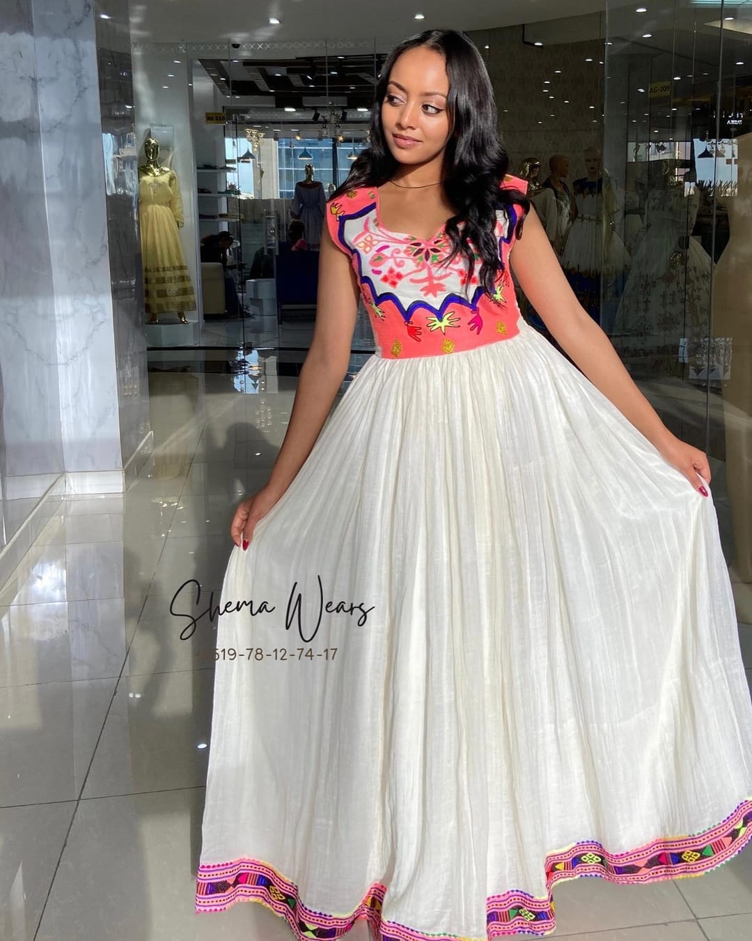 ሞዴል፣ ላዕለዋይ ክፋሉ ሮዛን ብርቱኳናውን ጥበብን ጫፉ ሕብራዊ ጥበብን ዘለዎ፣ ኢድ ዘይብሉ ጻዕዳ ሓበሻ ቀሚሽ ተኸዲና