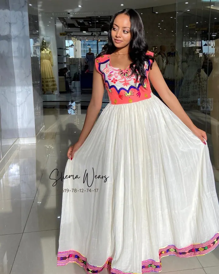 Model in a sleeveless white habesha kemis with a pink and orange tibeb bodice and a colourful tibeb hem