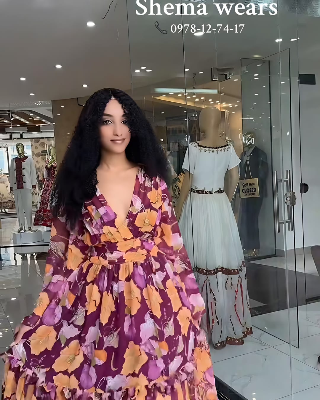 Model in a long plum chiffon dress with a marigold floral print, deep V neckline and tiered skirt