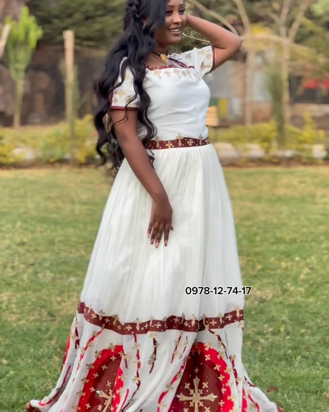 ሞዴል፣ ኣርባዕተ-ኩርናዕ ክሳድ፣ ሓጺር ኢድ፣ ቀይሕ ቅናትን ዓበይቲ ቀይሕ ሜዳልያታት ዘለዎ ታሕተዋይ ክፋልን ዘለዎ ጻዕዳ ሓበሻ ቀሚሽ ተኸዲና
