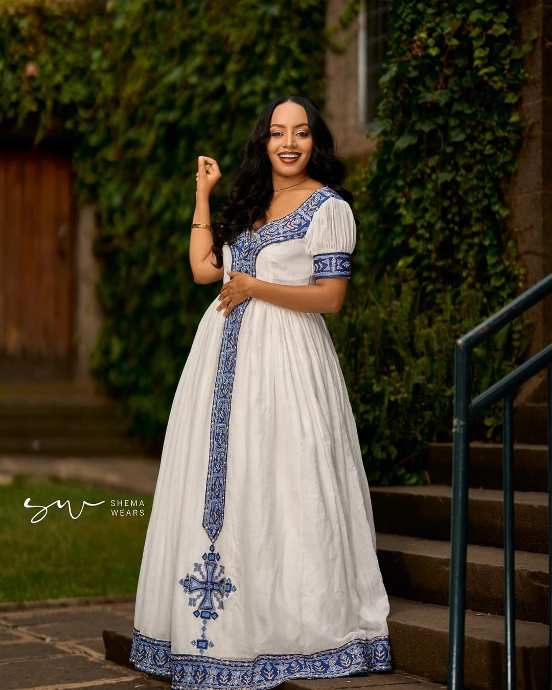 Woman in a white habesha kemis with royal blue tibeb at the neckline, puff sleeves and a centre panel ending in a cross