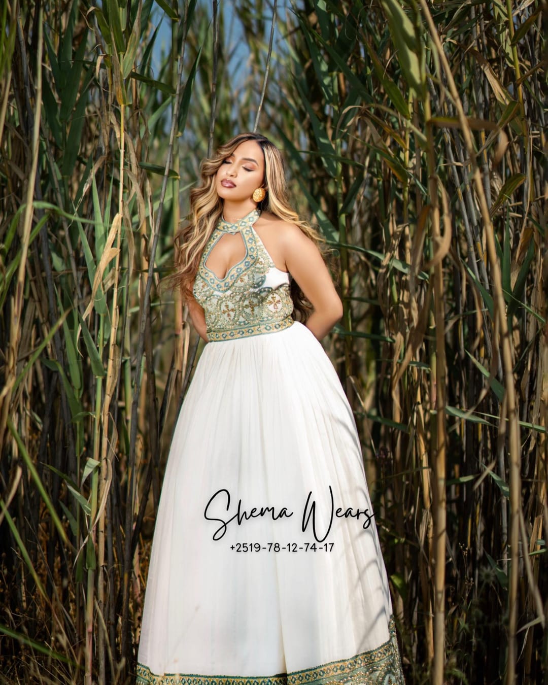 Model in a white halter-neck habesha kemis with a sage green and gold tibeb bodice and hem