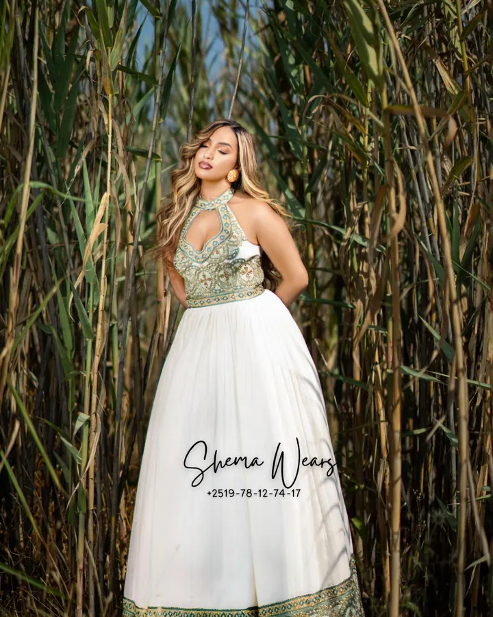 Model in a white halter-neck habesha kemis with a sage green and gold tibeb bodice and hem