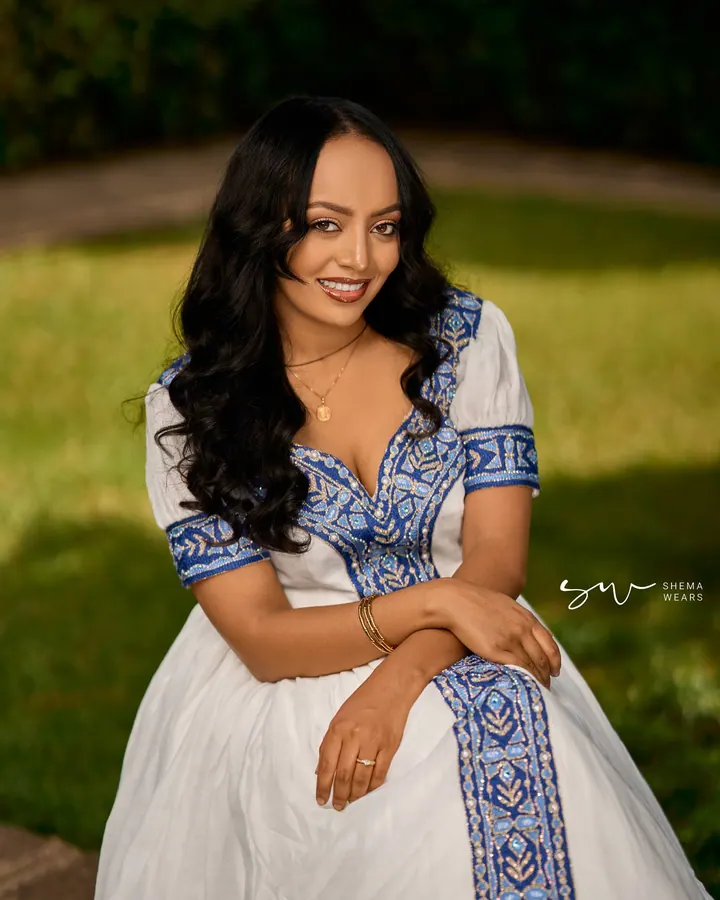 One of the two sisters who founded Shema Wears, in a white habesha kemis with blue tibeb