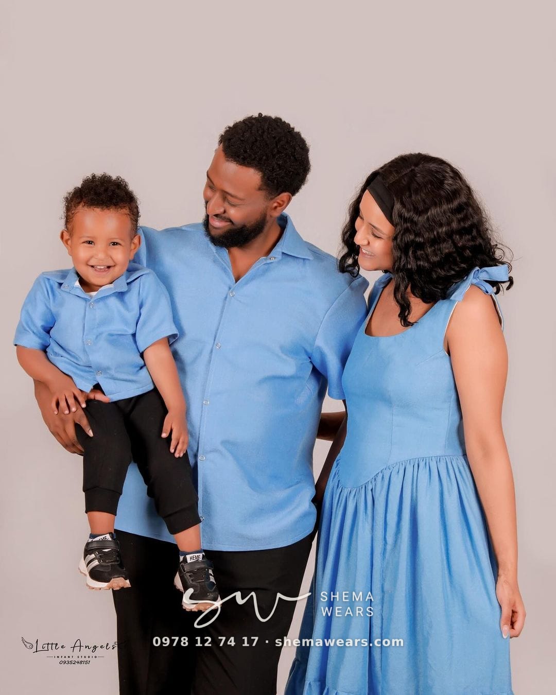 A family in matching sky blue — the mother in a long tiered dress, the father and son in blue shirts