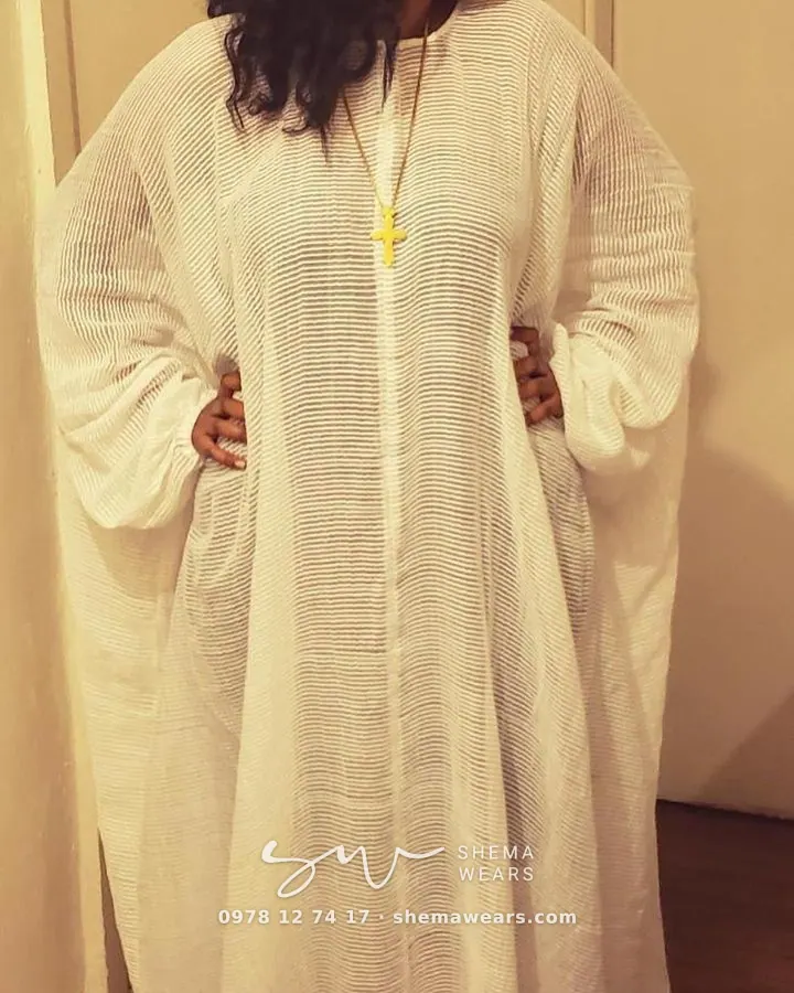 Woman in an oversized white gauze shema kaftan with long sleeves