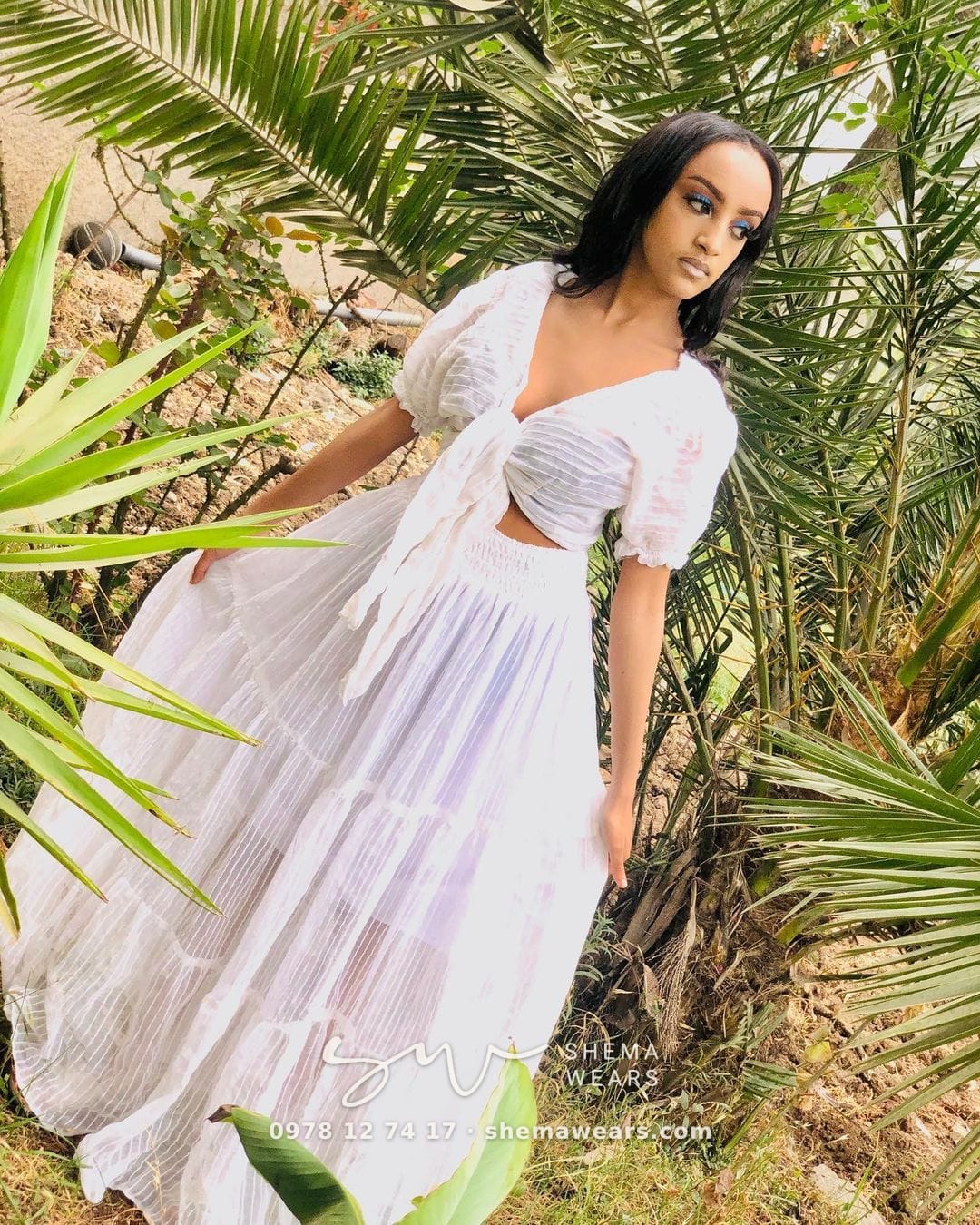 Model in a white two-piece set — a tie-front puff-sleeve crop top and a long flowing skirt