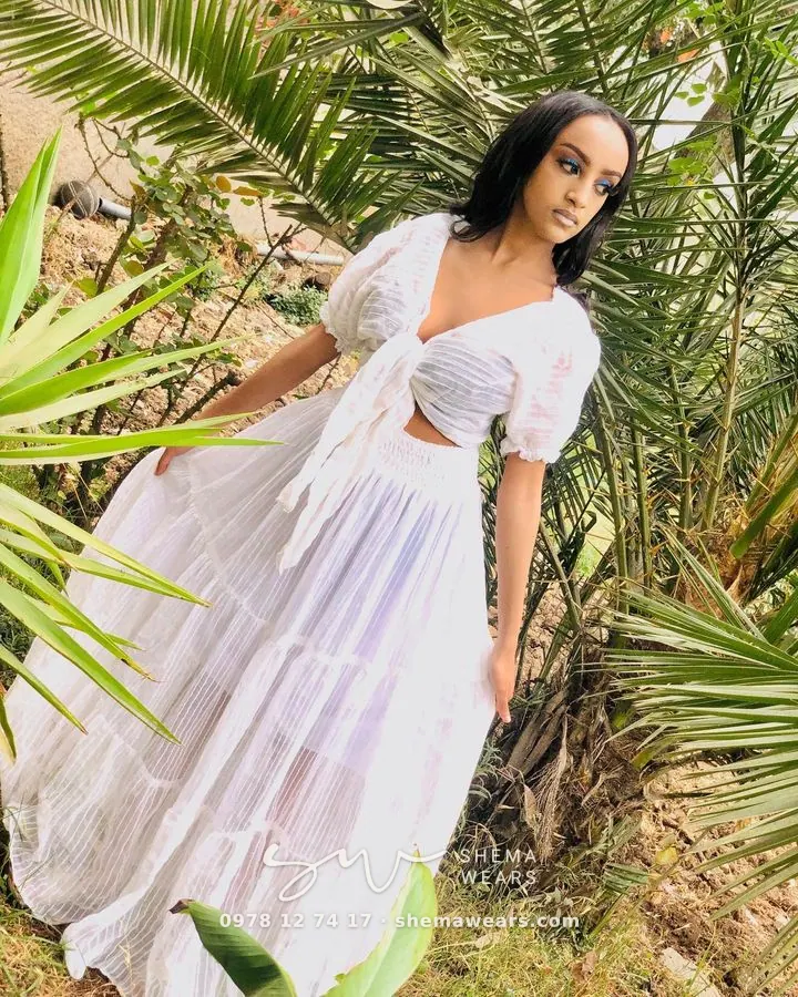 Model in a white two-piece set — a tie-front puff-sleeve crop top and a long flowing skirt